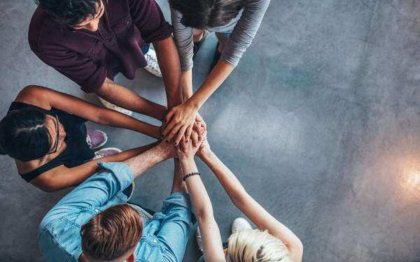 Group of people putting their hands in together