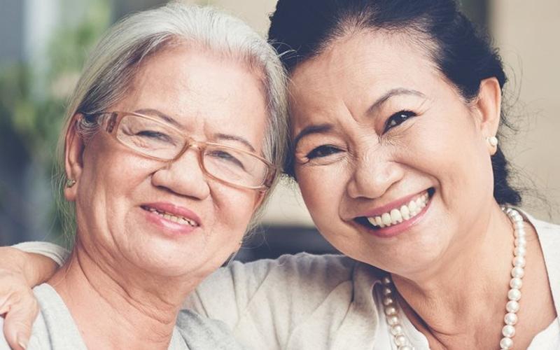 Femme âgée aux côtés d'une autre femme tout sourire